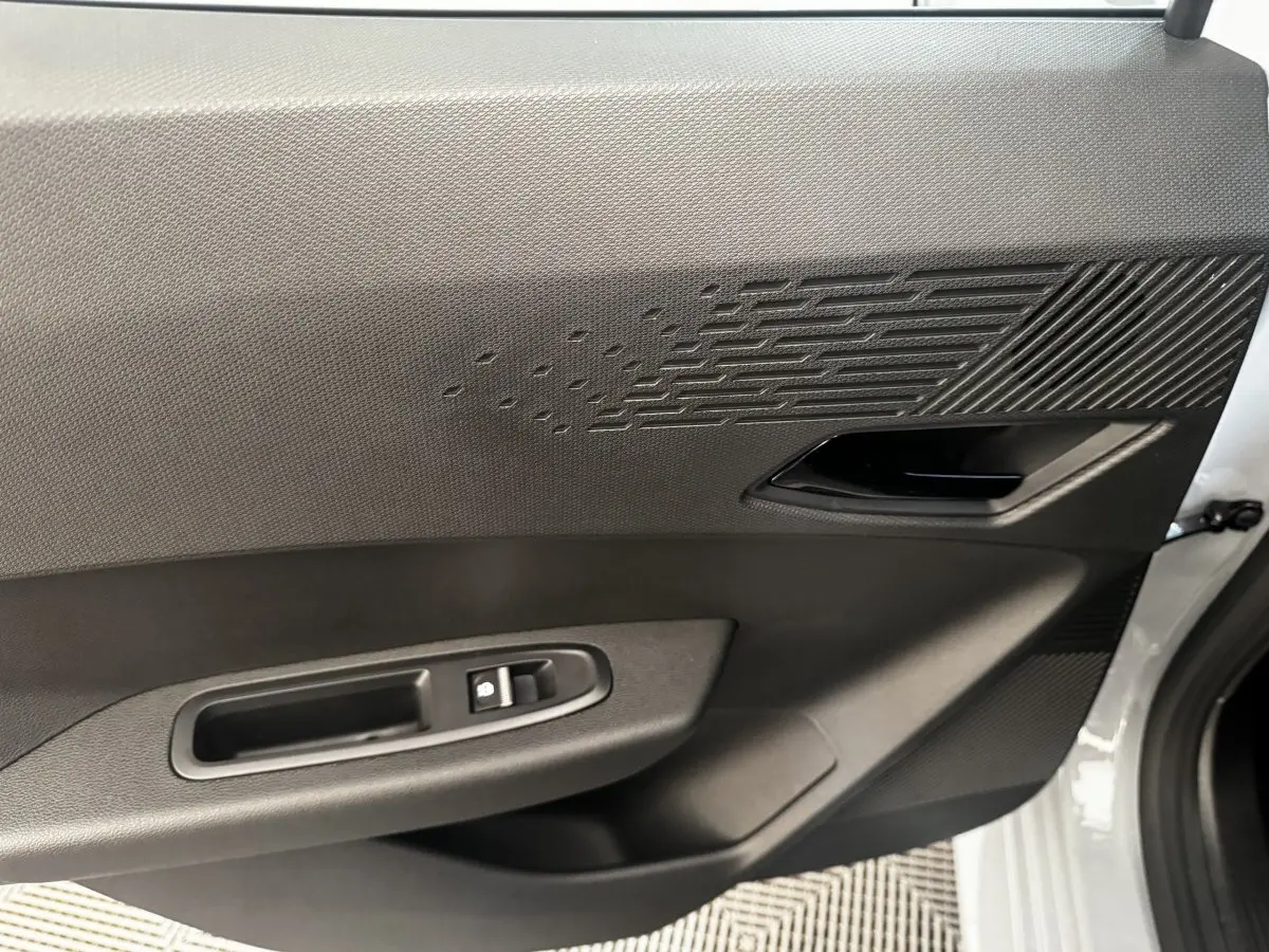 Gros plan sur la porte avant droite grise de la Renault Clio 2026, avec poignée intérieure et commande de vitre électrique.