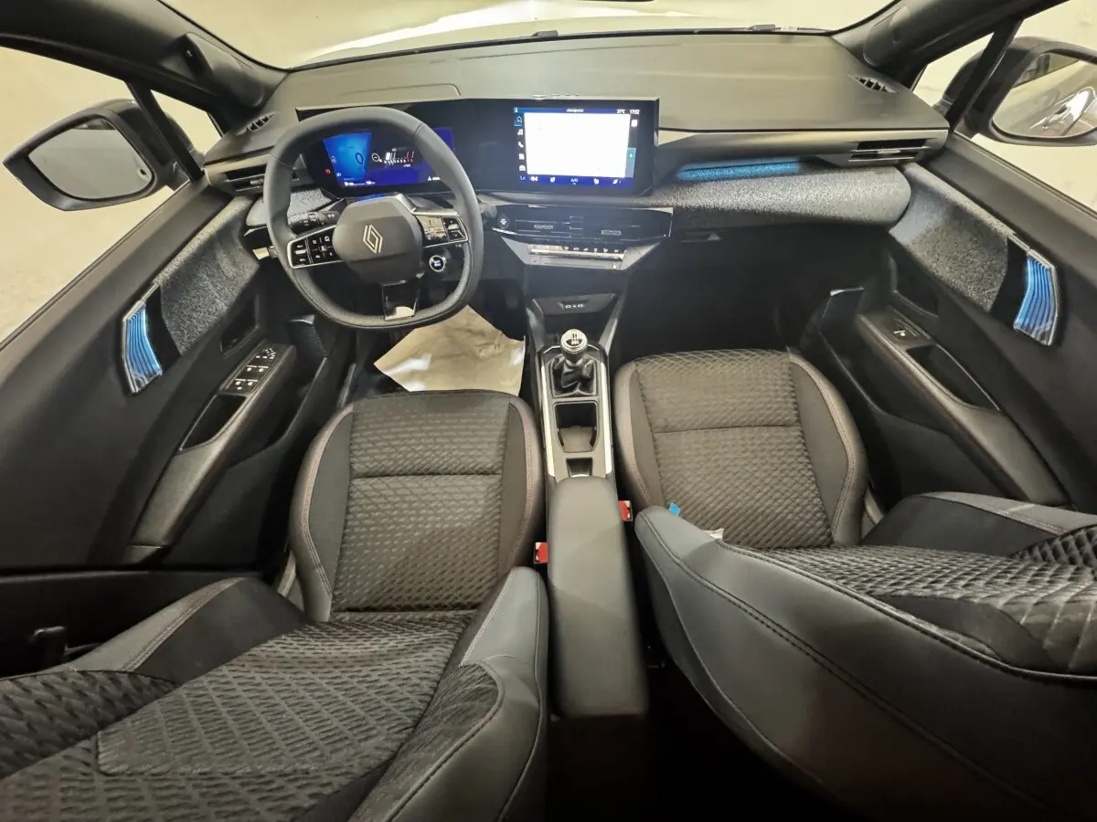 Vue intérieure avant de la Renault Clio Techno TCe 115, sièges noirs, volant multifonctions et écran tactile central.