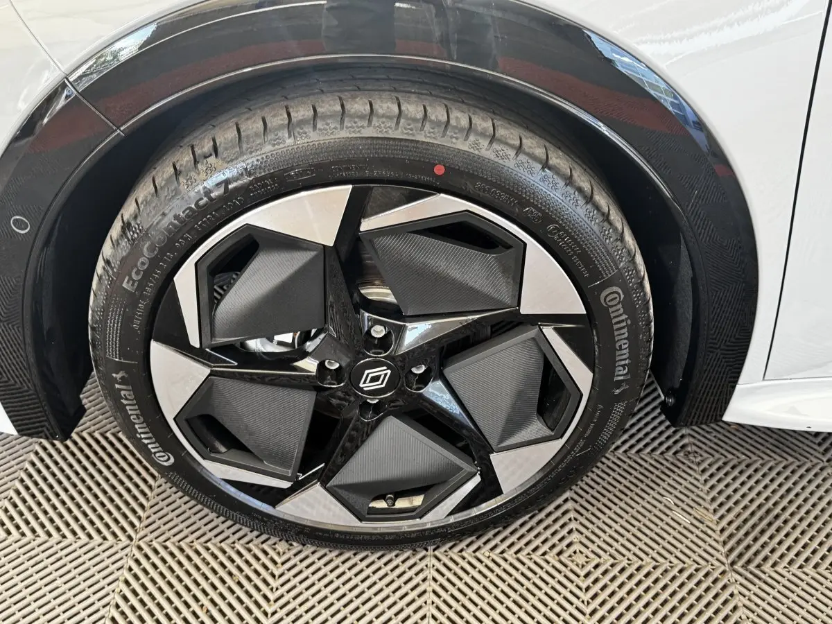 Gros plan sur la roue avant droite de la Renault Clio gris clair, avec jante noire et argent au design géométrique.