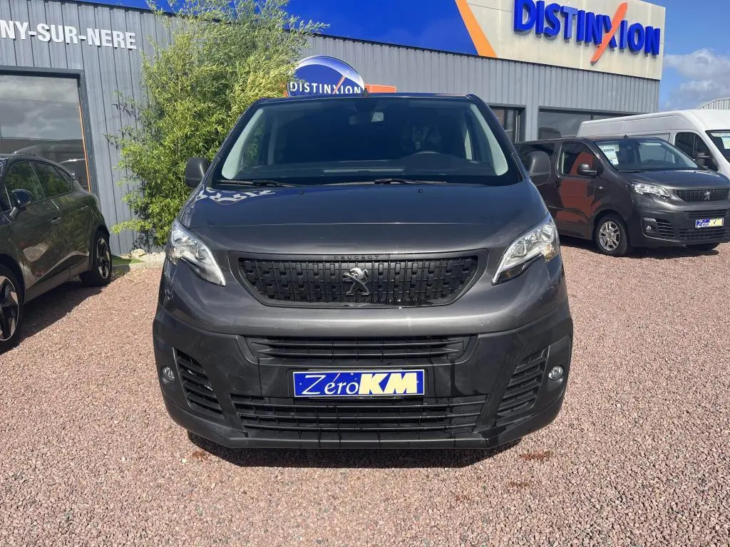 Vue frontale d'un Peugeot Expert Fourgon gris platinium métal avec calandre noire et plaque Zero KM.