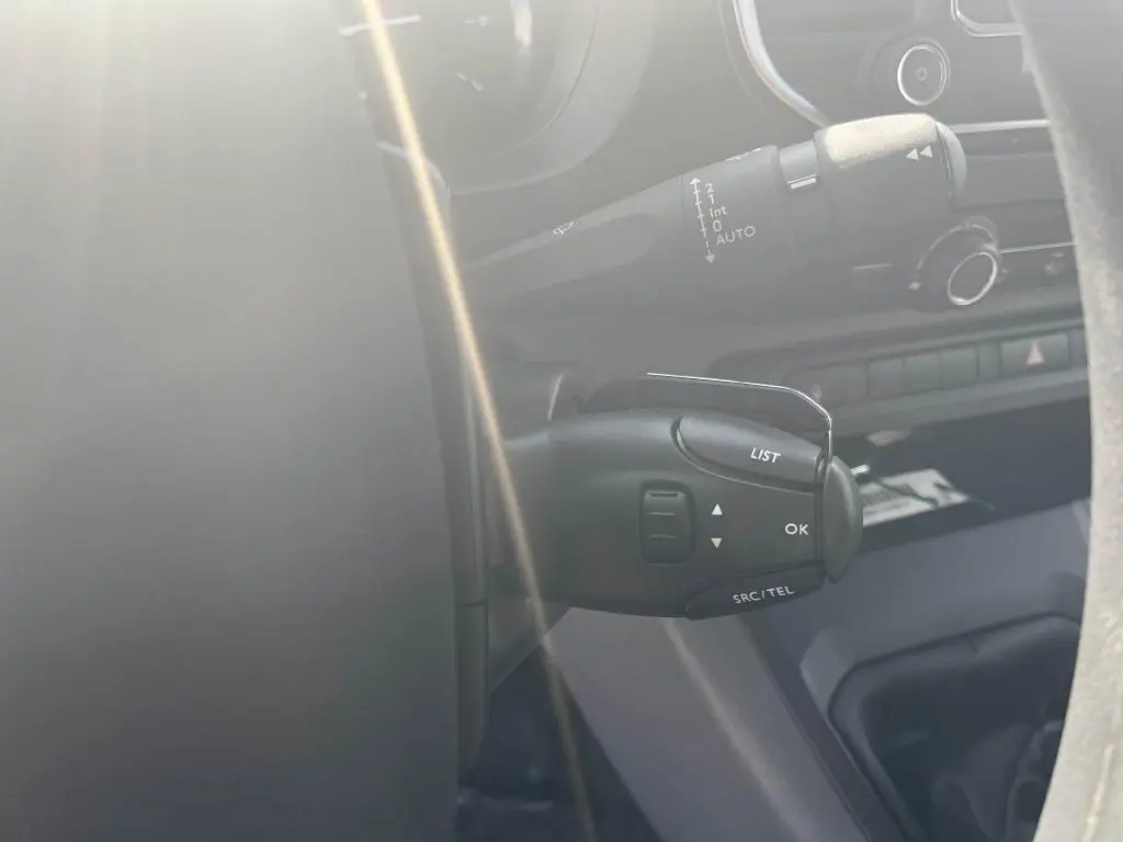 Gros plan sur la commande multifonction au volant du Peugeot Expert Fourgon gris platinium, intérieur côté conducteur.
