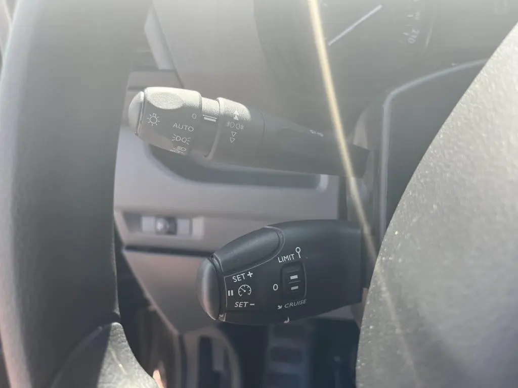 Gros plan sur les commandes de régulateur et feux automatiques du Peugeot Expert Fourgon gris platinium 2023.