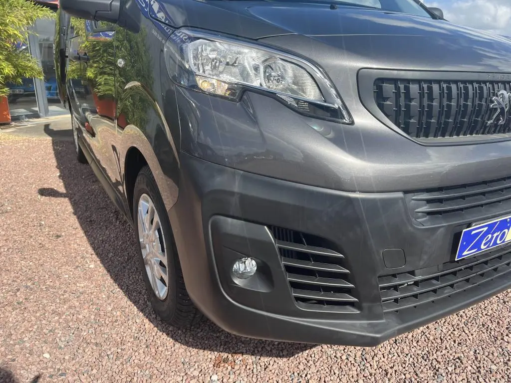 Vue 3/4 avant droit du Peugeot Expert Fourgon gris platinium métal avec projecteurs antibrouillard et calandre noire.