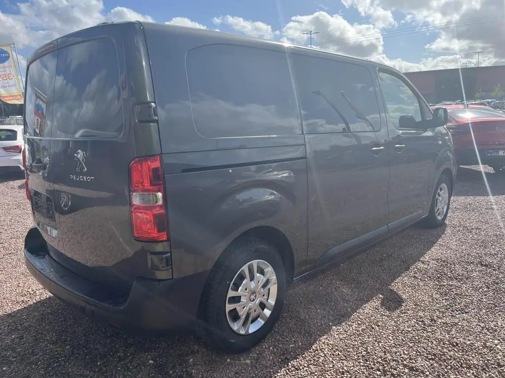 Vue 3/4 arrière droit d'un Peugeot Expert Fourgon gris platinium métallisé avec portes latérales et feux arrière visibles.