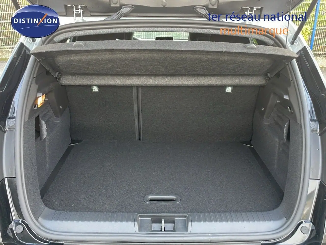 Coffre ouvert vu de l'arrière du Renault Captur noir étoile métal avec toit gris, espace de chargement vide et propre.