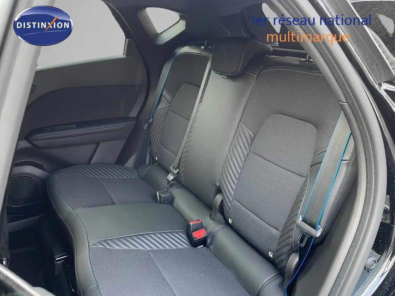 Vue intérieure arrière du Renault Captur noir étoile avec sellerie mixte cuir et tissu noir soulignée de surpiqûres bleues.