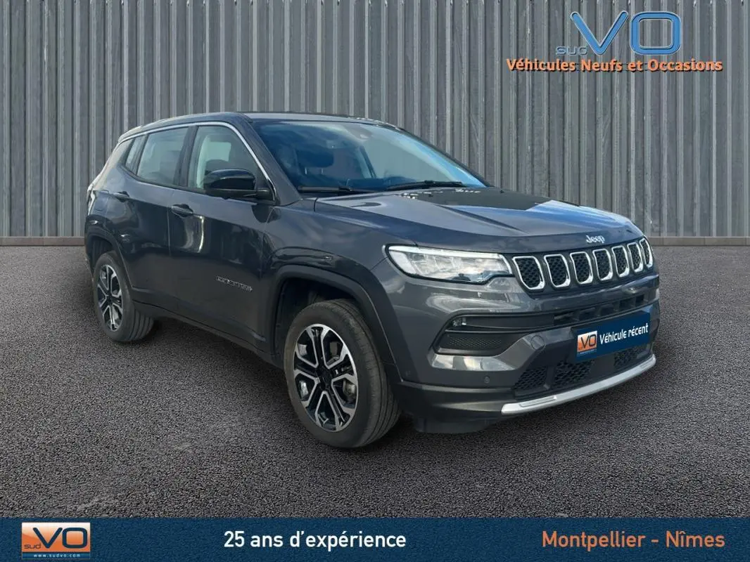 Jeep Compass gris 3/4 avant droit, SUV moderne avec calandre distinctive et jantes alliage bicolores.