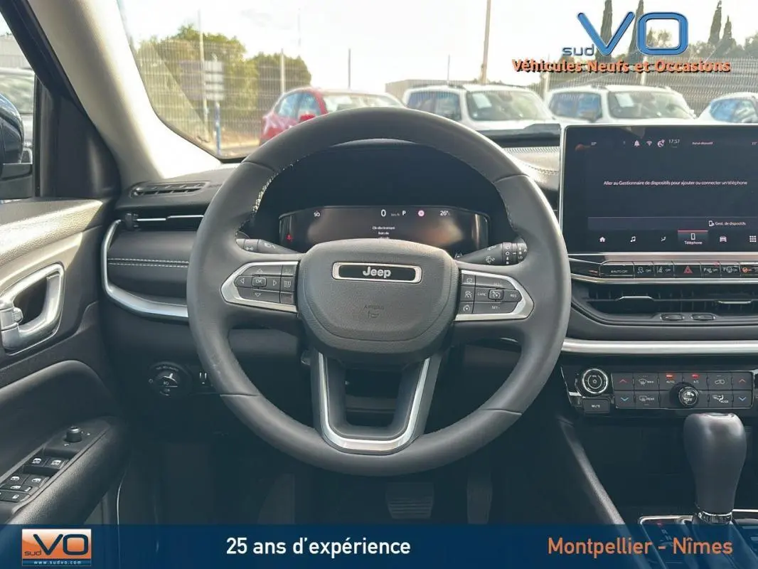 Vue centrée sur le volant et tableau de bord du Jeep Compass gris 2024 avec écran tactile et commandes au volant.