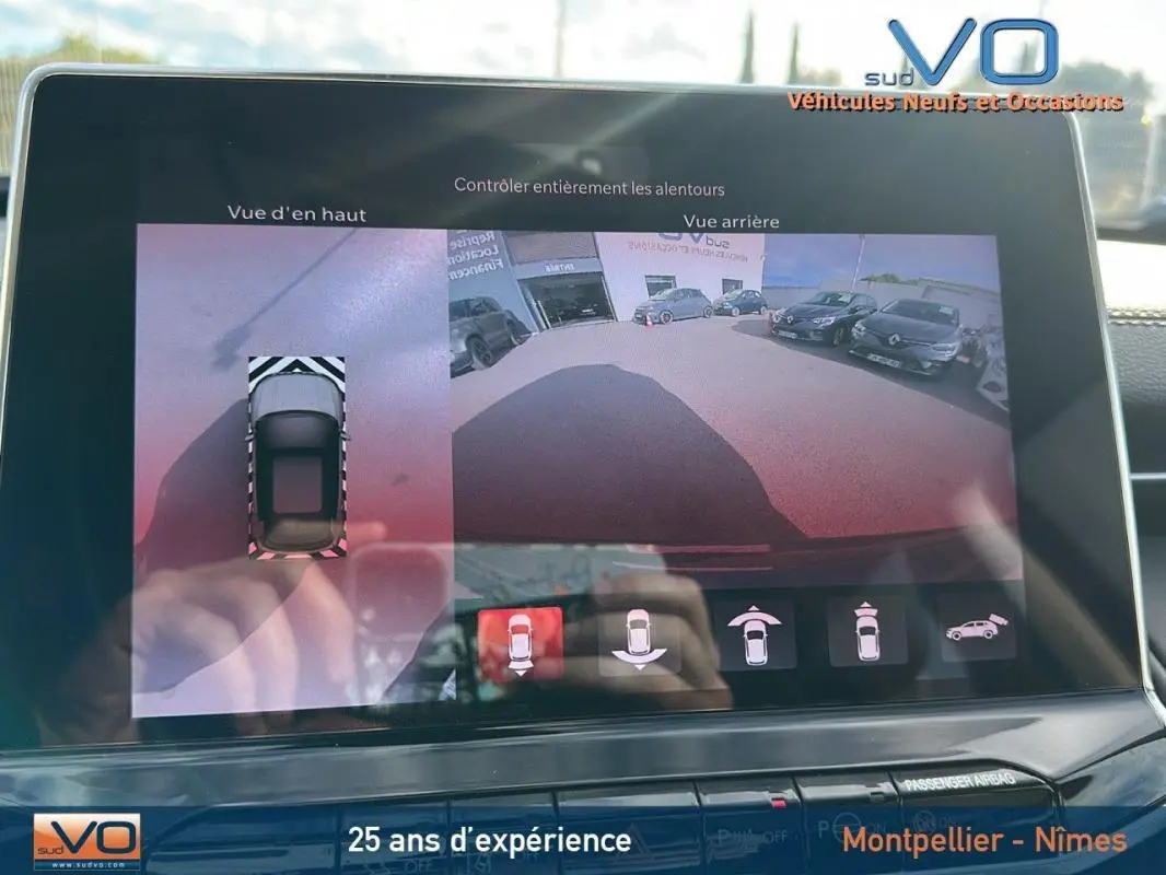 Écran tactile montrant la caméra de recul et vue en hauteur du Jeep Compass gris 2024 en stationnement.