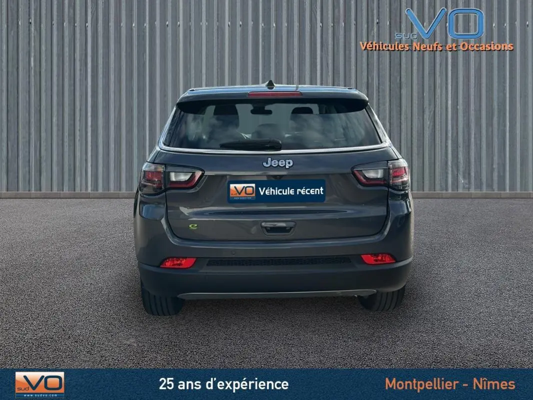 Vue arrière d'un Jeep Compass gris 2024 avec feux LED et logo Jeep bien visibles sur fond urbain.