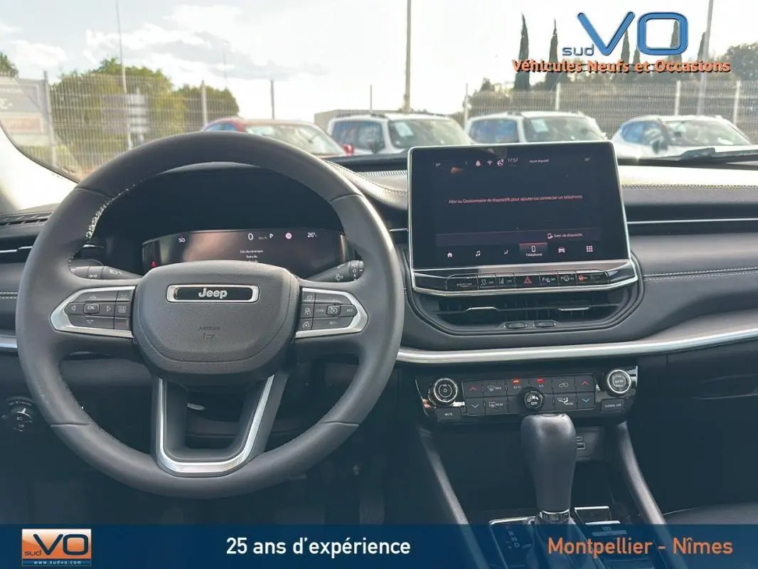 Vue intérieure du tableau de bord et volant du Jeep Compass gris 2024 avec écran tactile et commandes au volant visibles.