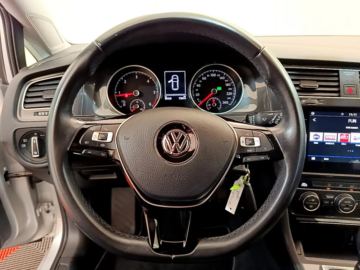 Vue rapprochée du volant cuir noir de la Volkswagen Golf gris clair 2019 avec tableau de bord et écran tactile visibles.