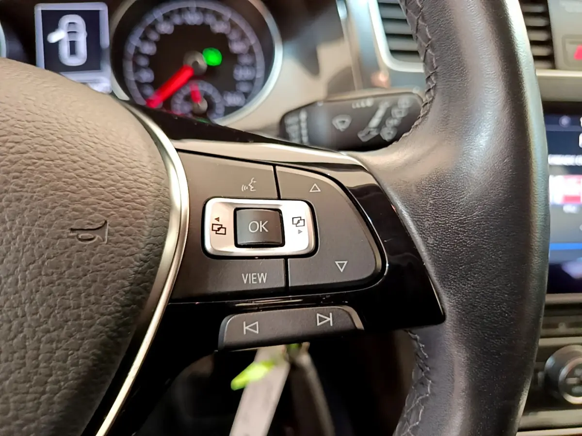 Gros plan sur les commandes du volant cuir de la Volkswagen Golf 2019, avec tableau de bord et écran tactile en arrière-plan.