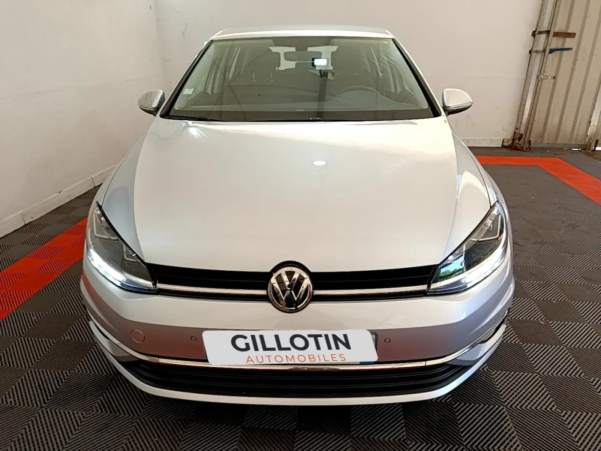 Vue frontale d'une Volkswagen Golf gris clair 2019 avec phares LED et calandre noire brillante.
