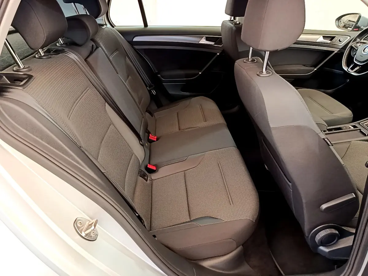 Vue intérieure côté gauche arrière de la Volkswagen Golf gris clair 2019, sièges tissu gris et tableau de bord visible.