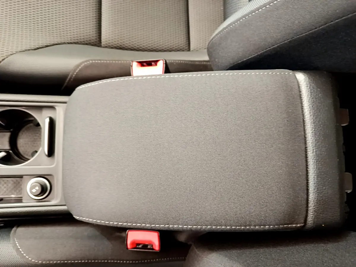 Vue rapprochée de l'accoudoir central gris foncé et des sièges noirs de la Volkswagen Golf 1.6 TDI 115 DSG7 Confort Business.