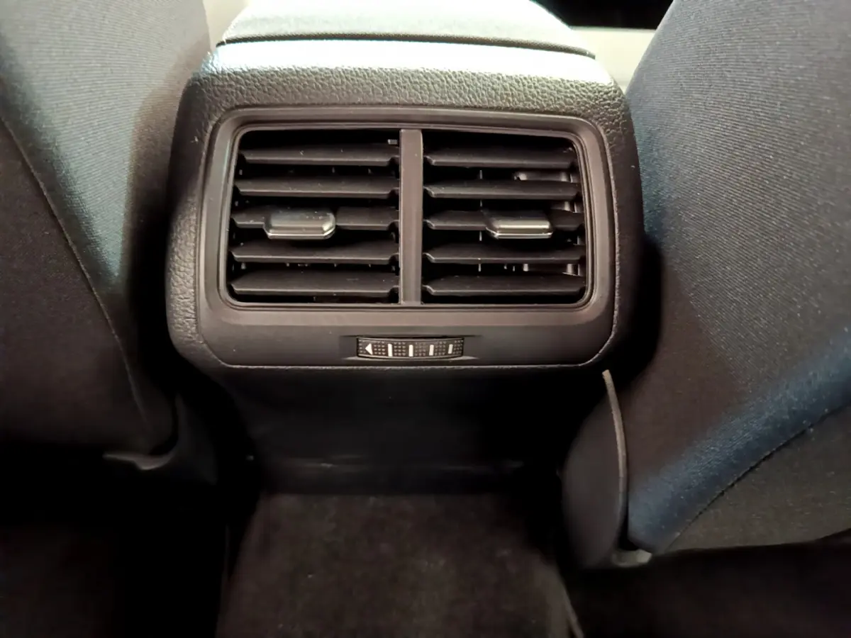 Grille d'aération arrière noire vue de face entre les sièges avant d'une Volkswagen Golf 2019 gris clair.