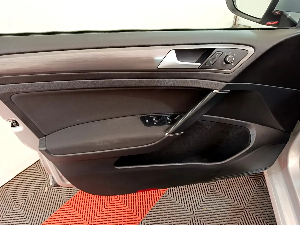Intérieur côté gauche de la porte avant d'une Volkswagen Golf gris clair, avec commandes de vitres et rétroviseurs.