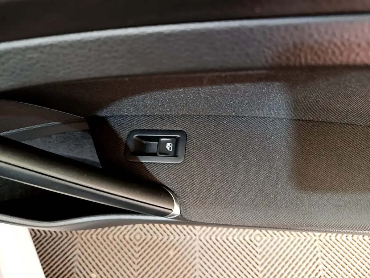 Détail de la commande d'ouverture du coffre sur la garniture intérieure noire d'une Volkswagen Golf gris clair 2019.