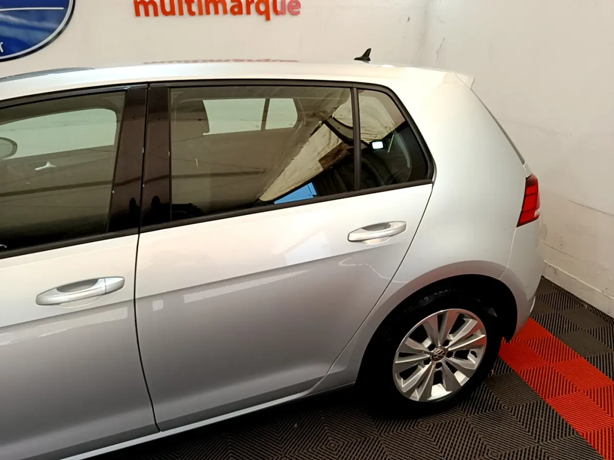 Profil côté droit d'une Volkswagen Golf gris clair 2019, mettant en valeur la porte arrière et la jante alliage.