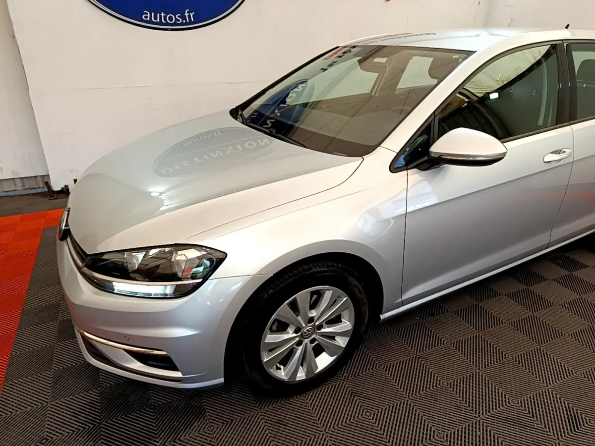 Vue 3/4 avant droit d'une Volkswagen Golf gris clair avec phares LED et jantes alliage visibles.