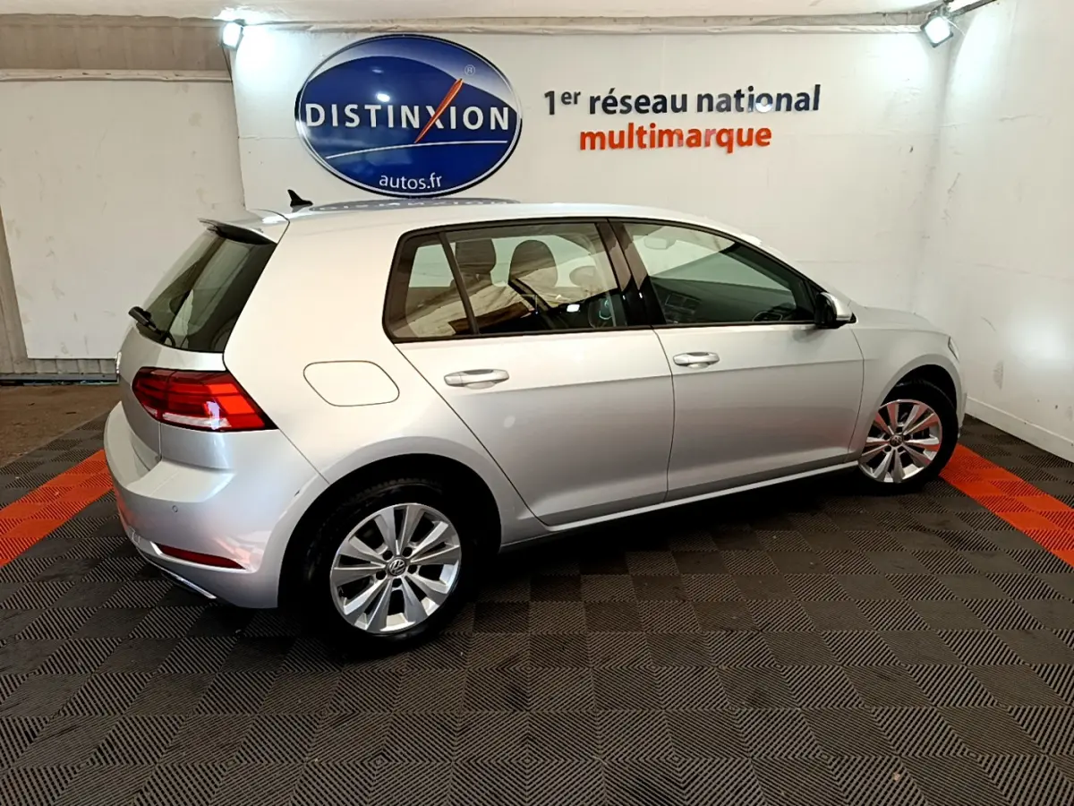 Vue côté droit arrière d'une Volkswagen Golf gris clair 2019 garée en intérieur avec jantes alliage et feux arrière LED.