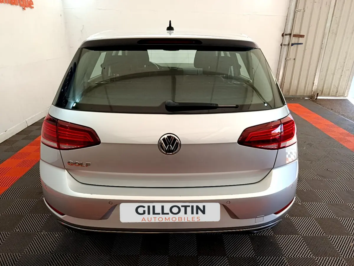 Vue arrière d'une Volkswagen Golf gris clair 2019 avec feux arrière rouges et logo VW centré.