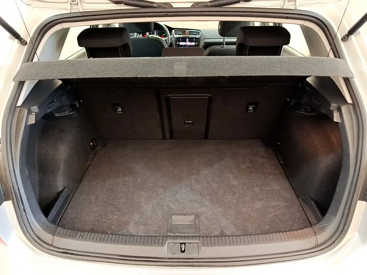 Coffre ouvert d'une Volkswagen Golf gris clair 2019, vue arrière montrant l'espace de chargement et la banquette arrière.