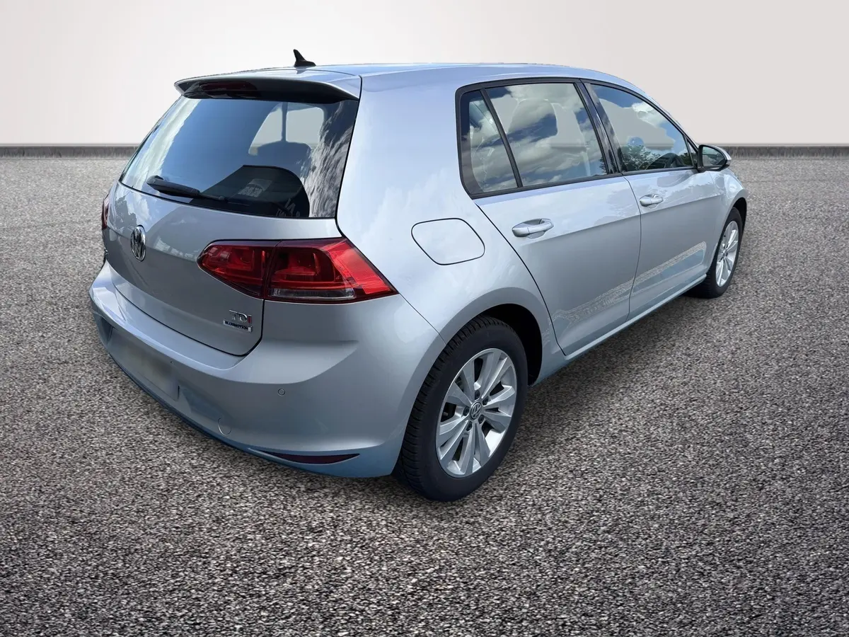 Vue 3/4 arrière droite d'une Volkswagen Golf gris clair, avec feux arrière LED et jantes alliage visibles.