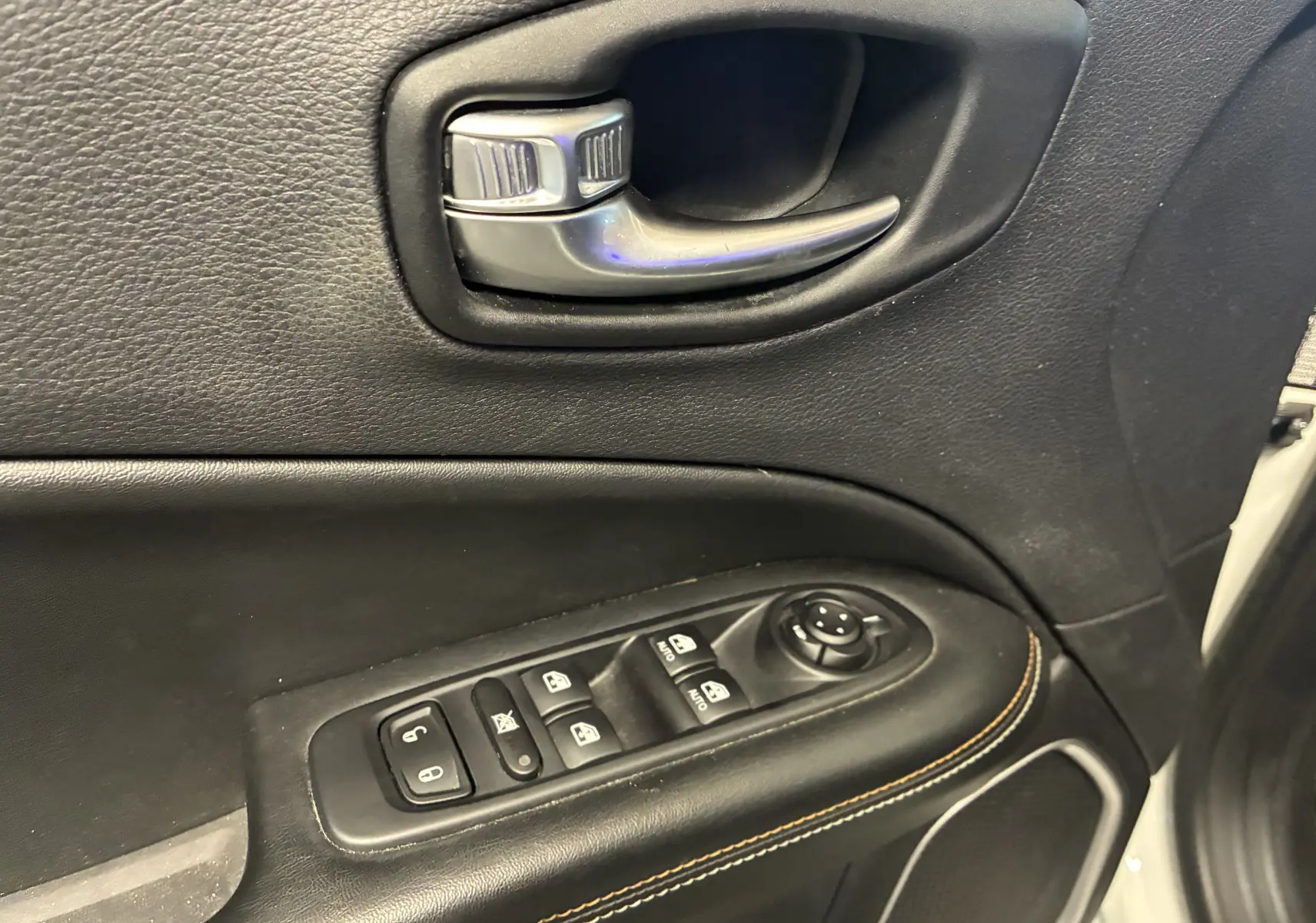Gros plan sur la poignée intérieure et les commandes de vitres côté conducteur du Jeep Compass ivoire 2021.