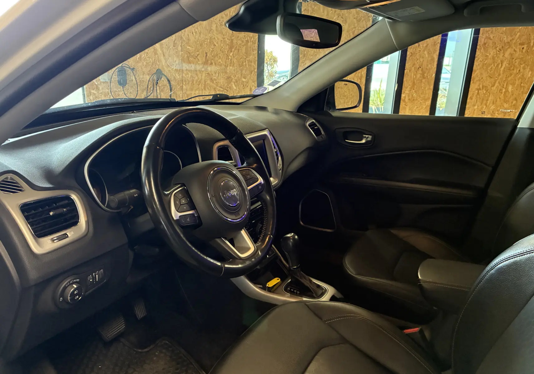 Vue intérieure côté conducteur du Jeep Compass 2021, volant cuir multifonctions et tableau de bord noir avec écran tactile.