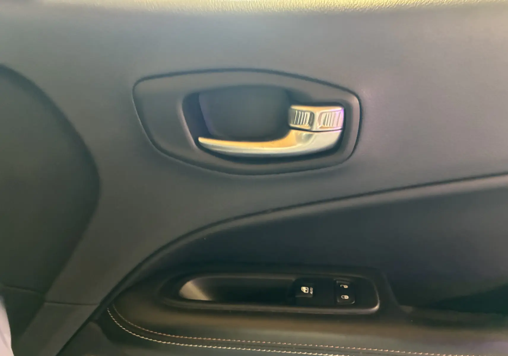 Gros plan sur la poignée intérieure et les commandes de verrouillage de la porte côté conducteur du Jeep Compass ivoire 2021.