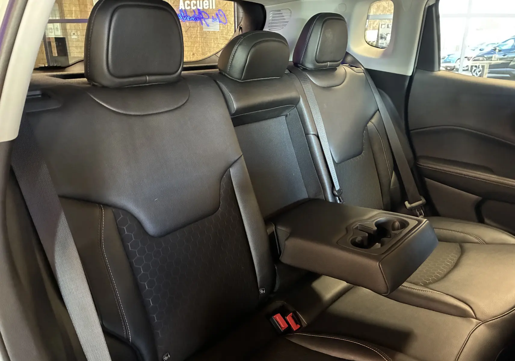 Vue intérieure arrière du Jeep Compass 2021, sièges noirs avec accoudoir central et porte-gobelets déployé.