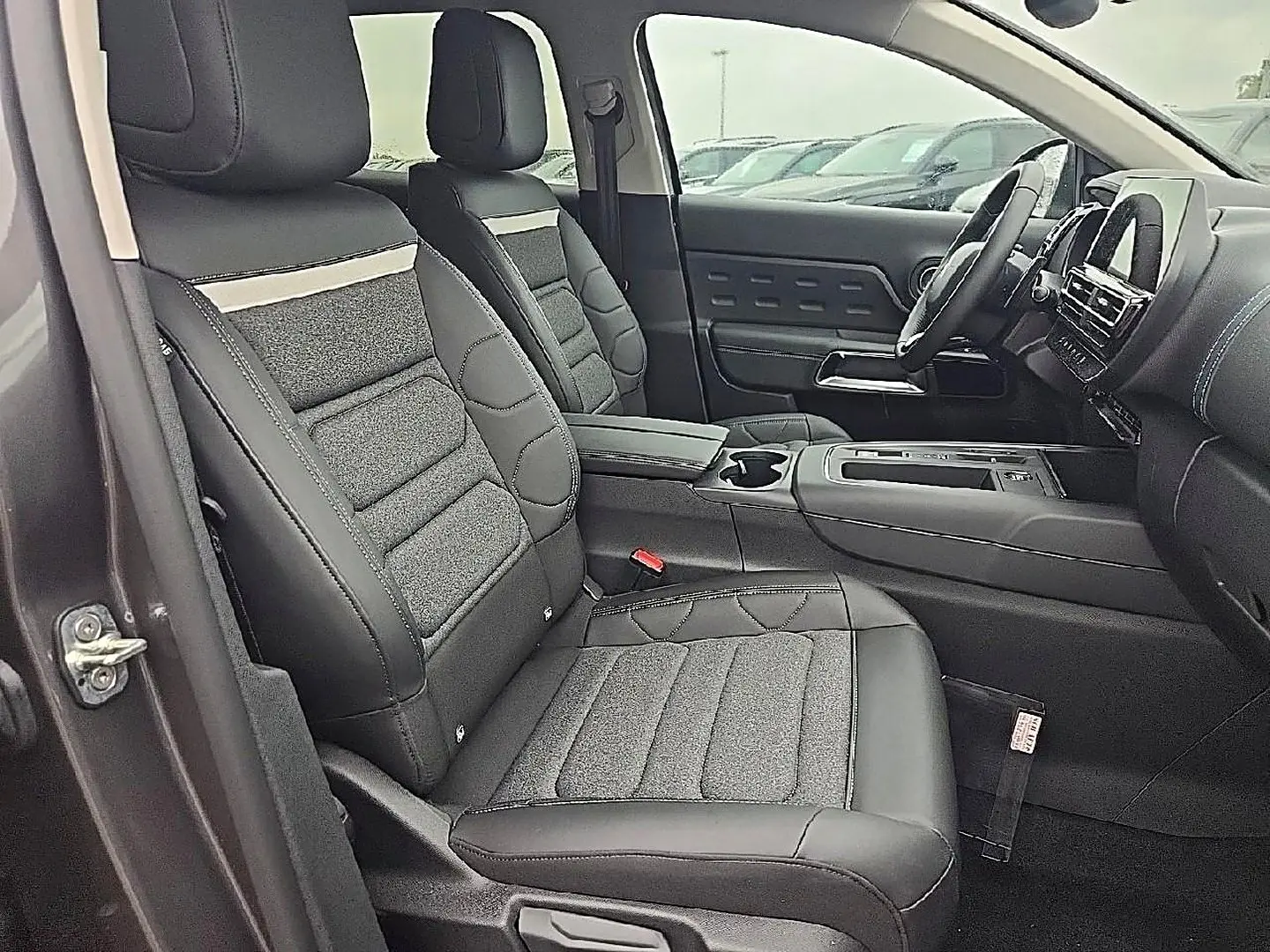 Vue intérieure côté conducteur du Citroën C5 Aircross gris 2025, sièges avant en cuir et tissu avec accoudoir central.