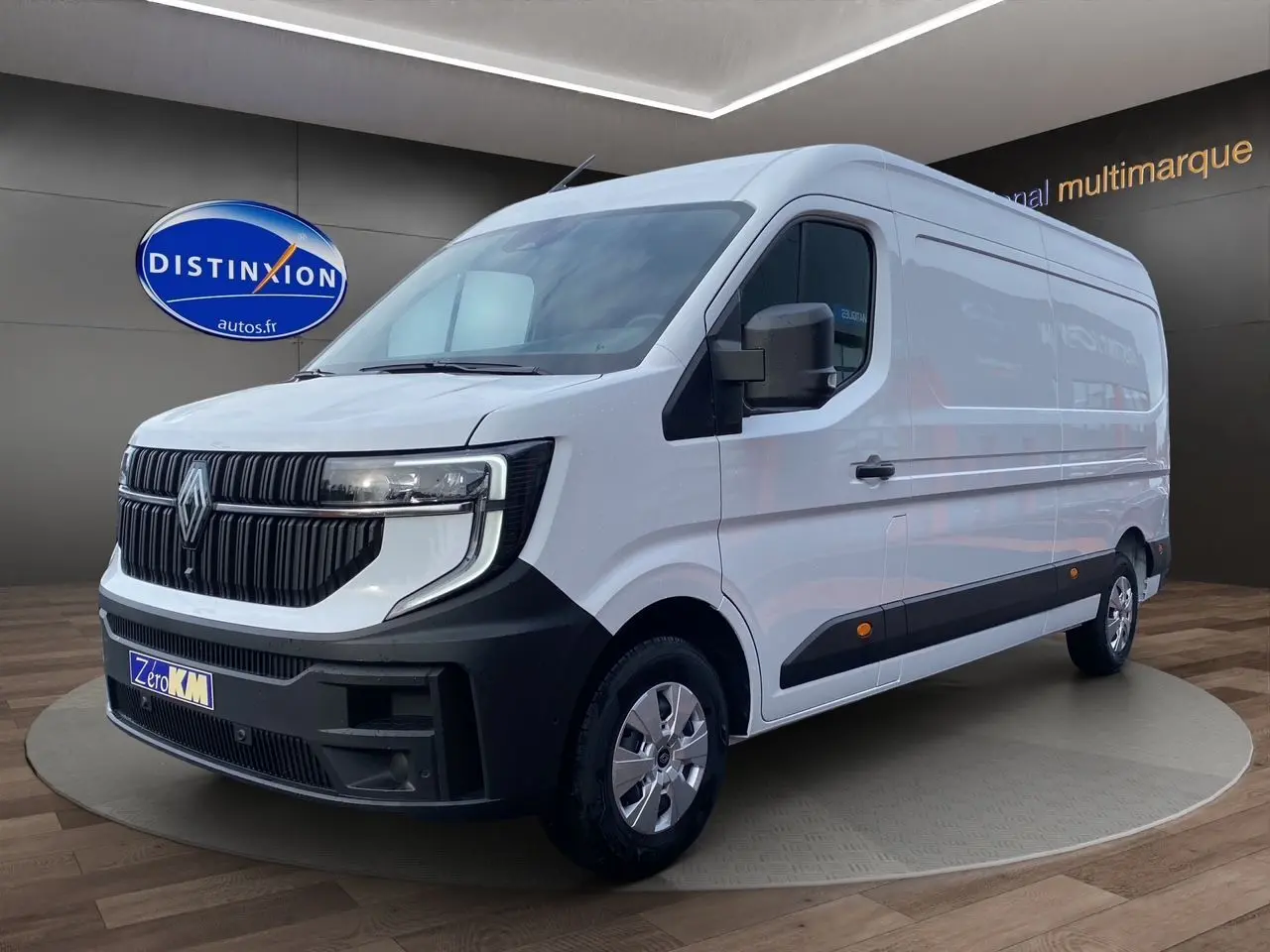 Renault Master blanc en 3/4 avant droit, avec calandre noire et jantes argentées, sur fond intérieur showroom.