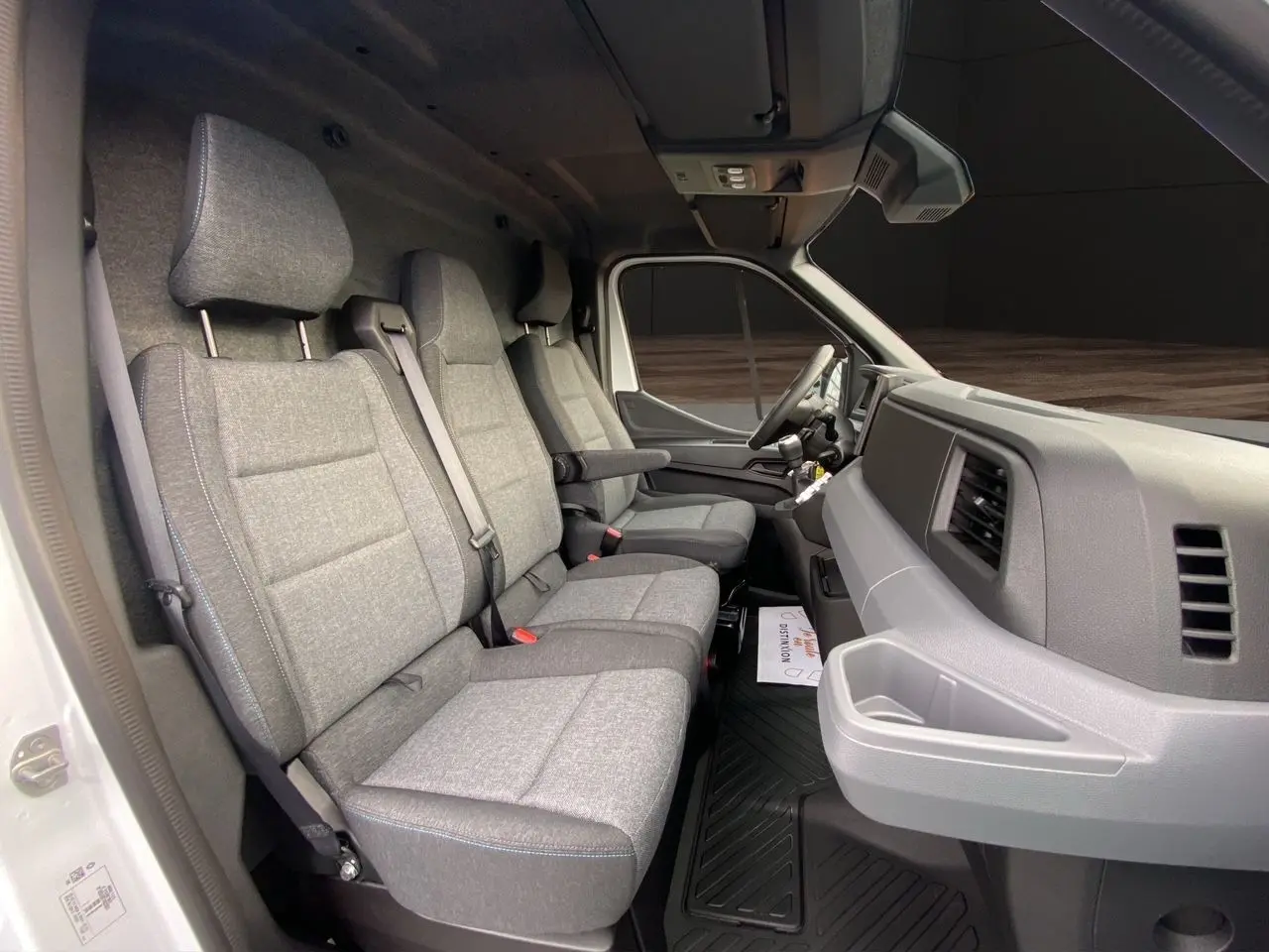 Vue intérieure côté passager du Renault Master blanc 2025, montrant la banquette grise à trois places et le tableau de bord.