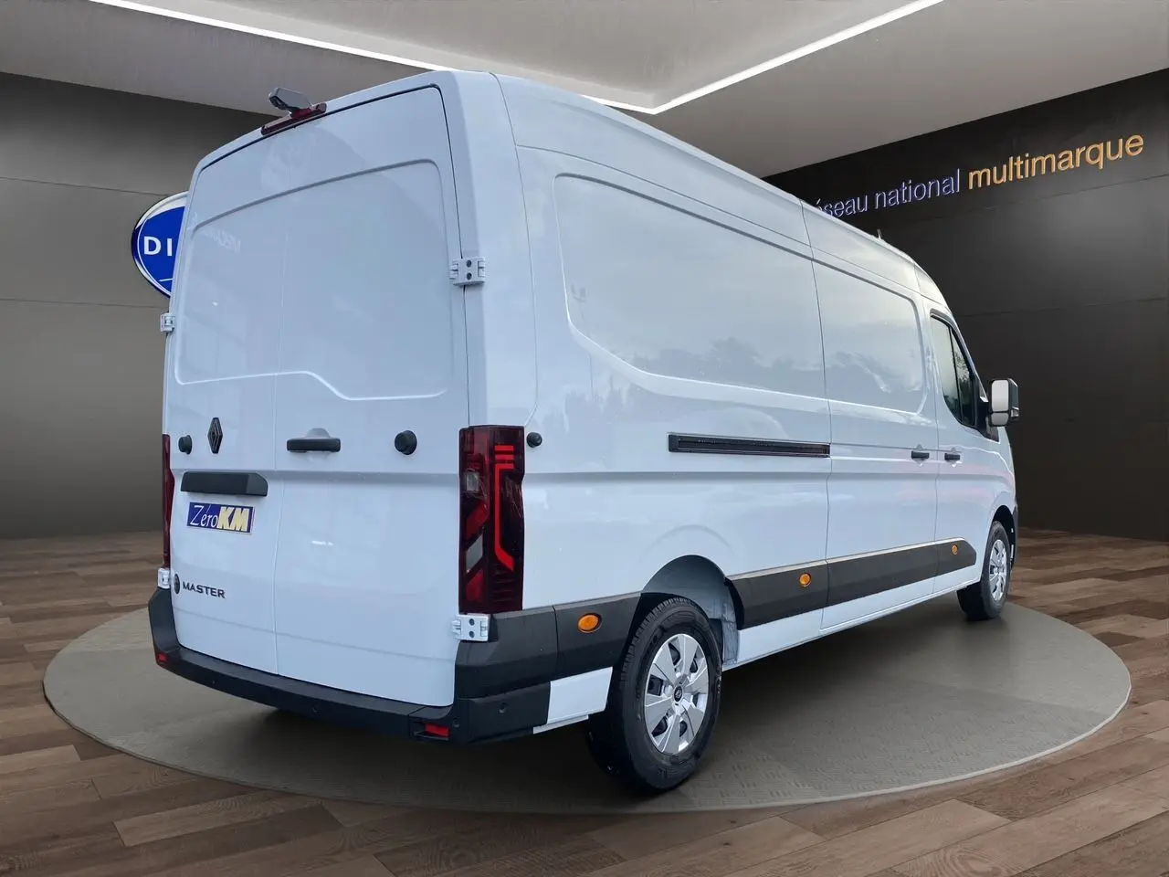 Vue 3/4 arrière droite du Renault Master blanc avec portes arrière tôlées et enjoliveurs noirs sur fond intérieur showroom.