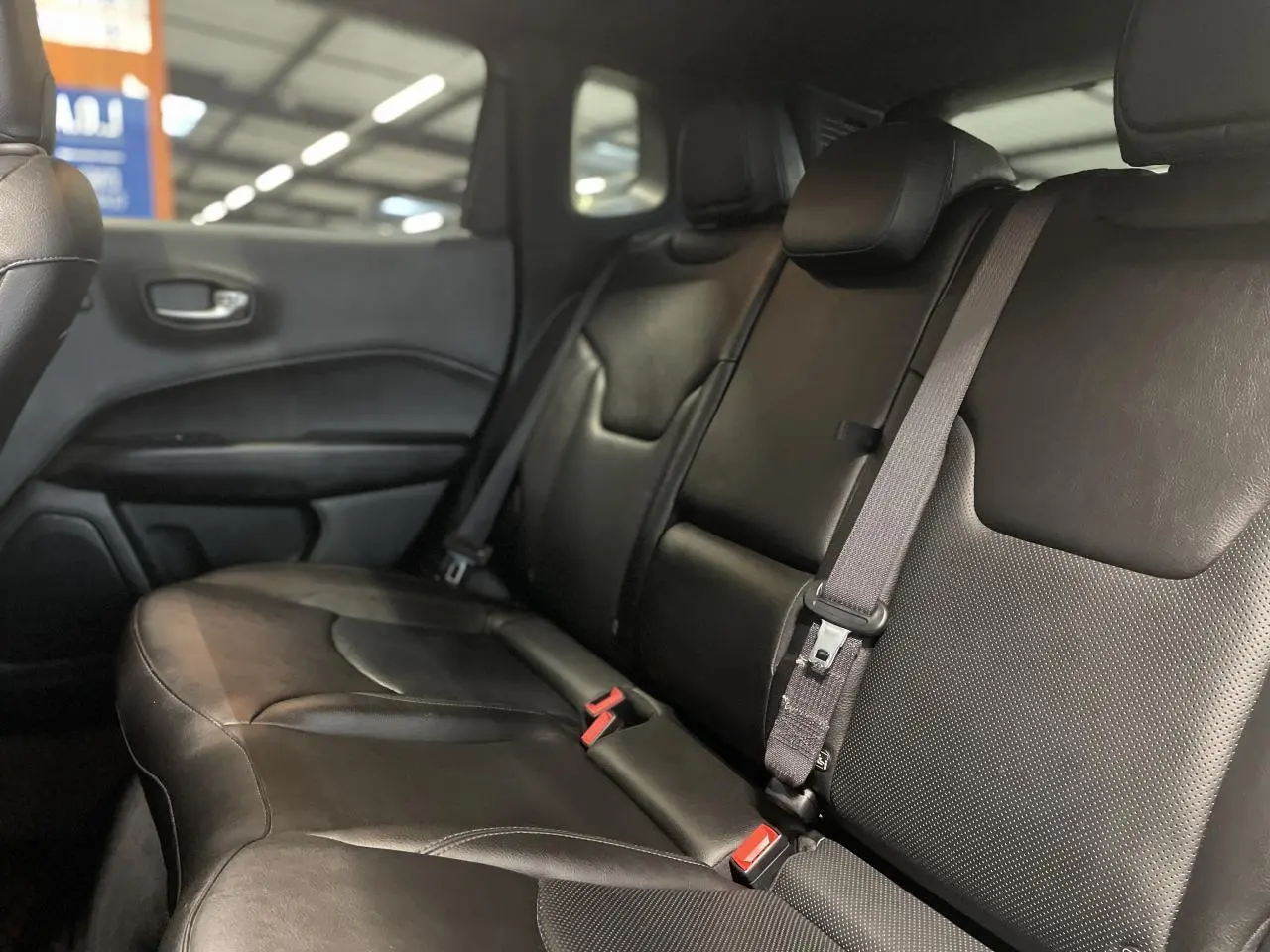 Vue latérale intérieure des sièges arrière en cuir noir du Jeep Compass Trailhawk 2021 avec ceinture de sécurité grise.