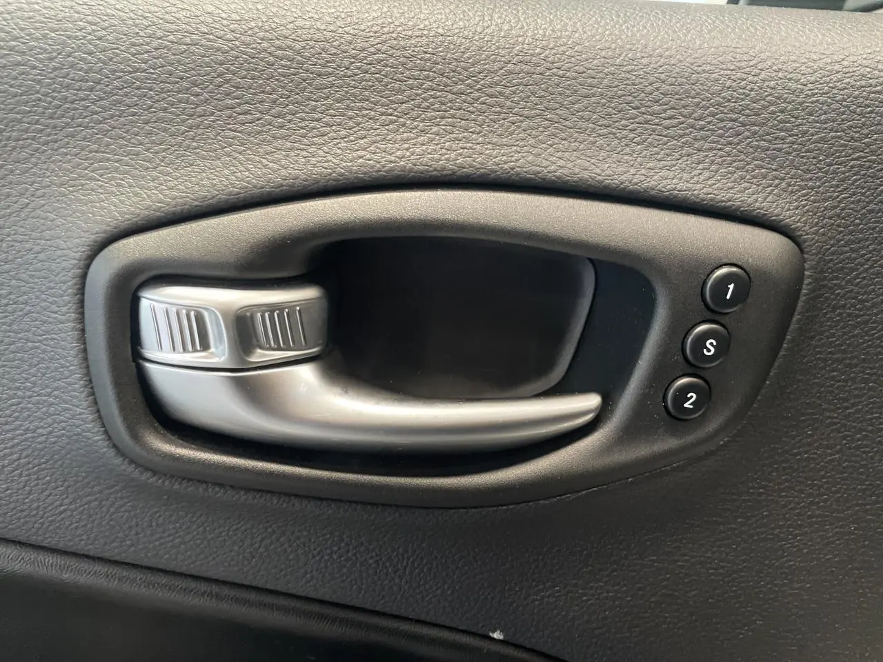 Poignée intérieure de porte noire avec commandes de réglage mémoire des sièges sur Jeep Compass Trailhawk gris foncé.