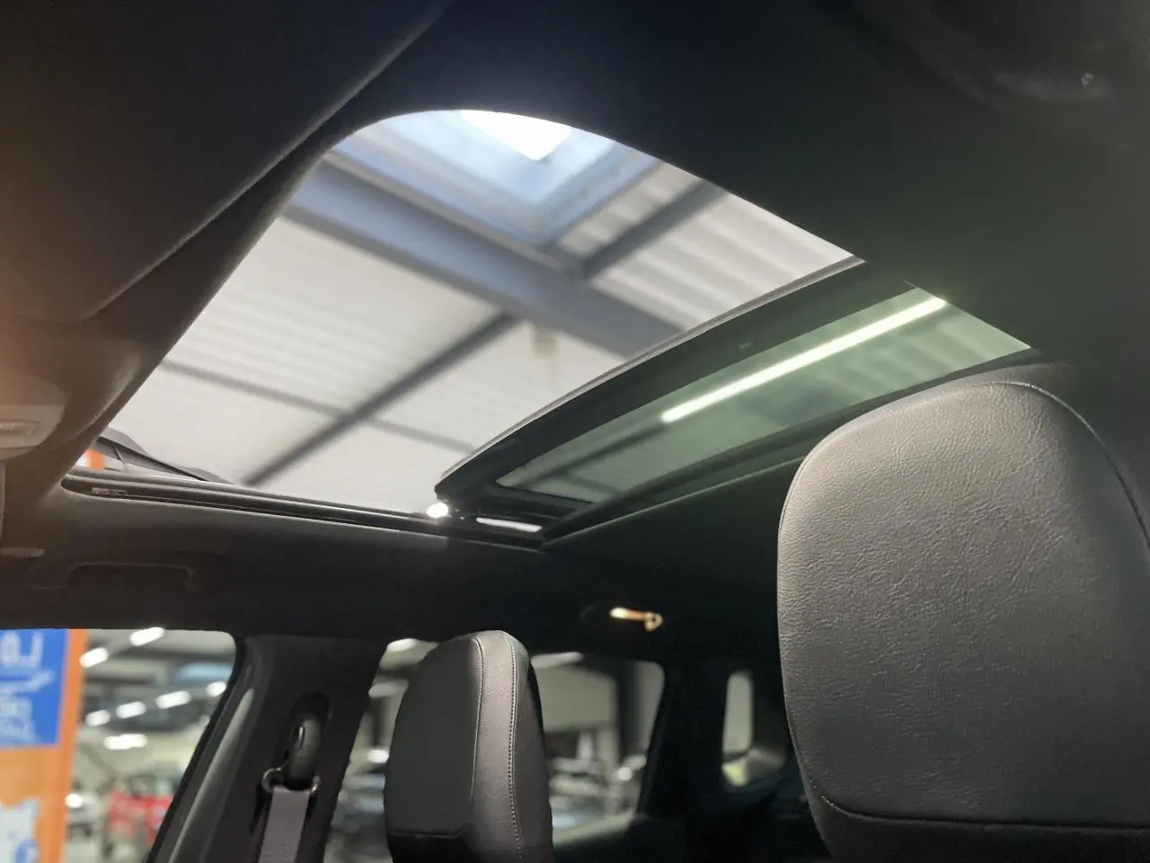 Toit ouvrant panoramique ouvert sur l'intérieur noir cuir du Jeep Compass Trailhawk 2021 en gris foncé.