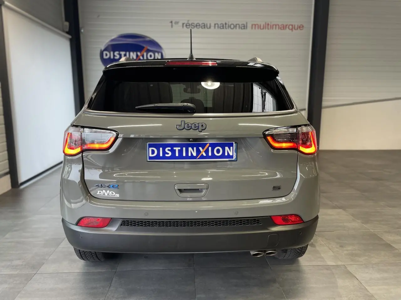 Vue arrière d'un Jeep Compass gris foncé avec feux arrière allumés et double sortie d'échappement visible.