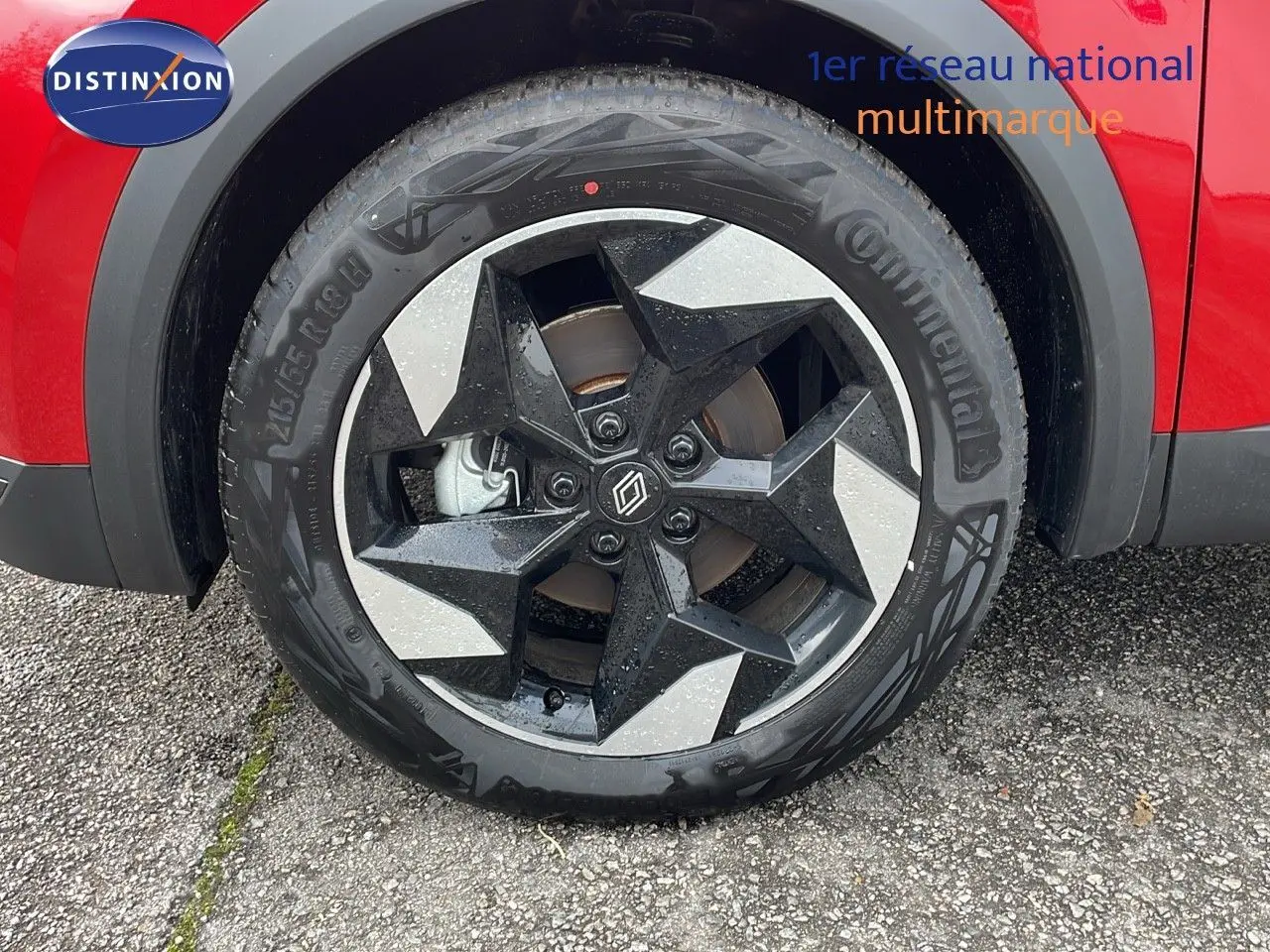 Gros plan sur la roue avant gauche du Renault Captur E-Tech rouge passion avec jante alliage noire et argentée.