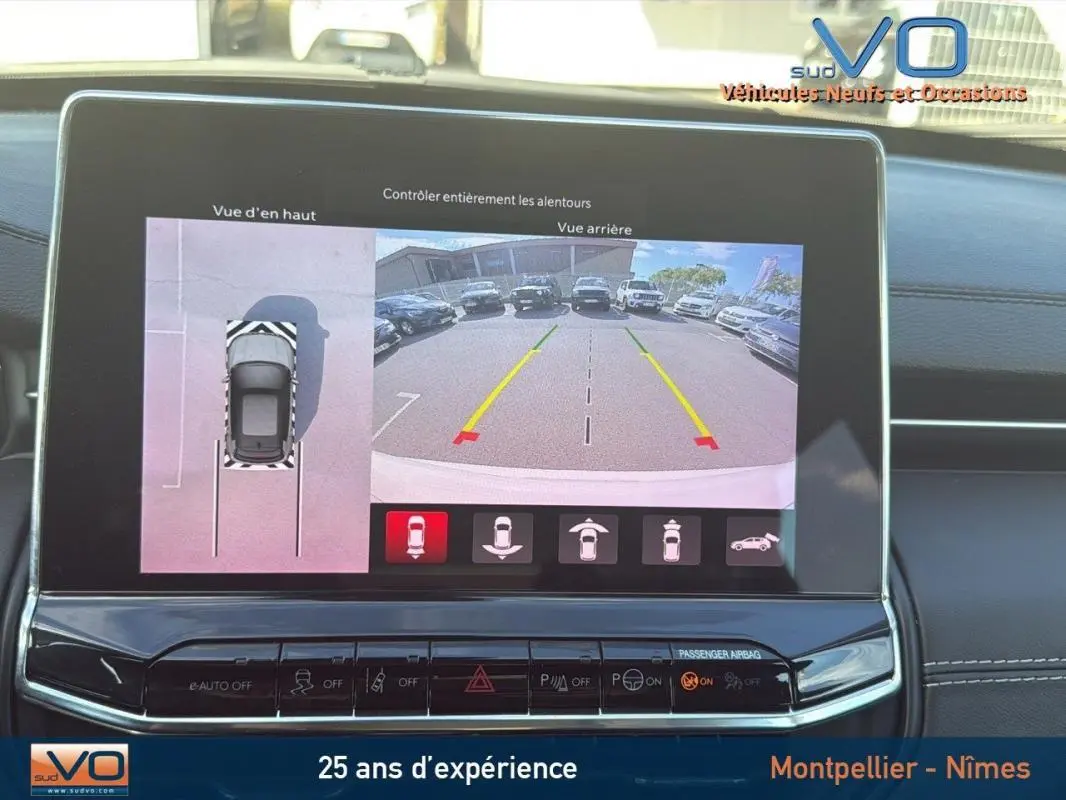 Écran tactile du Jeep Compass blanc 2024 montrant la caméra de recul et la vue en hauteur du stationnement.