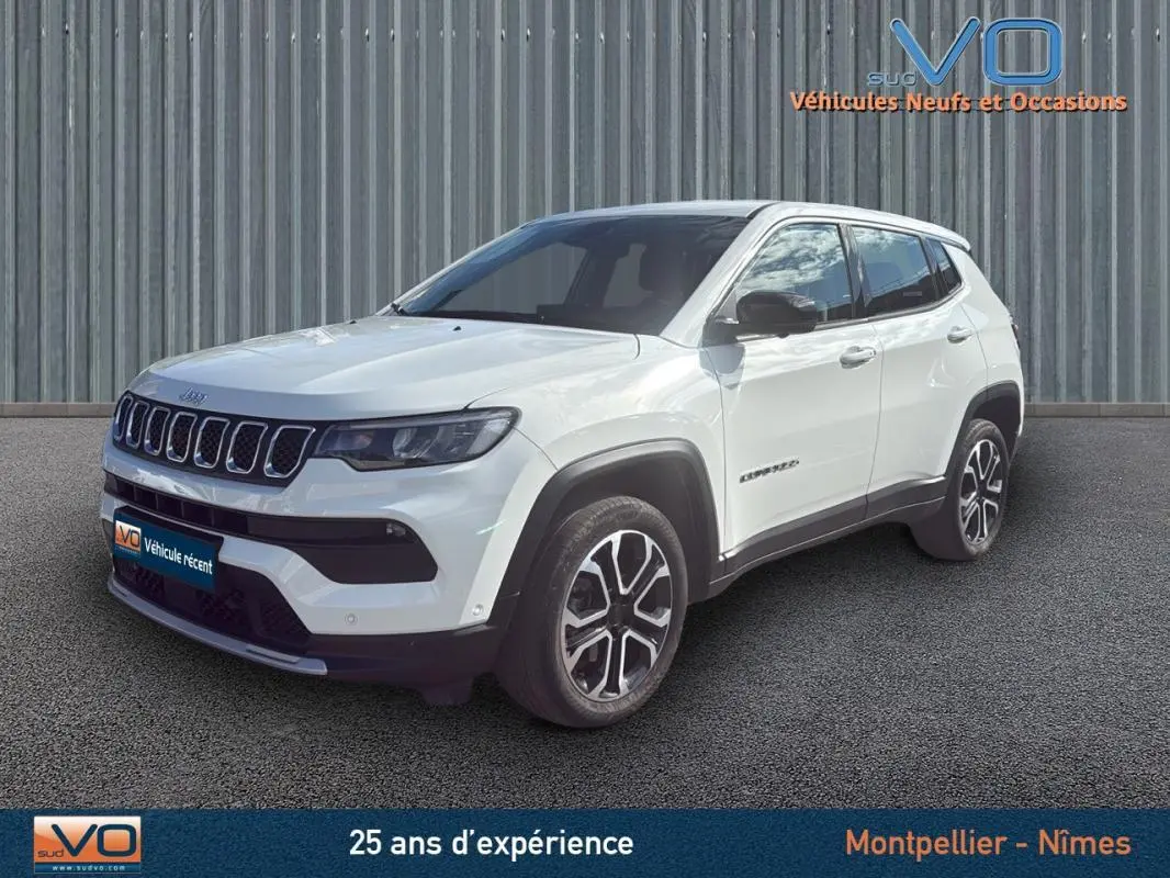 Jeep Compass blanc en 3/4 avant droit, jantes alliage 18 pouces et calandre distinctive sur fond urbain.