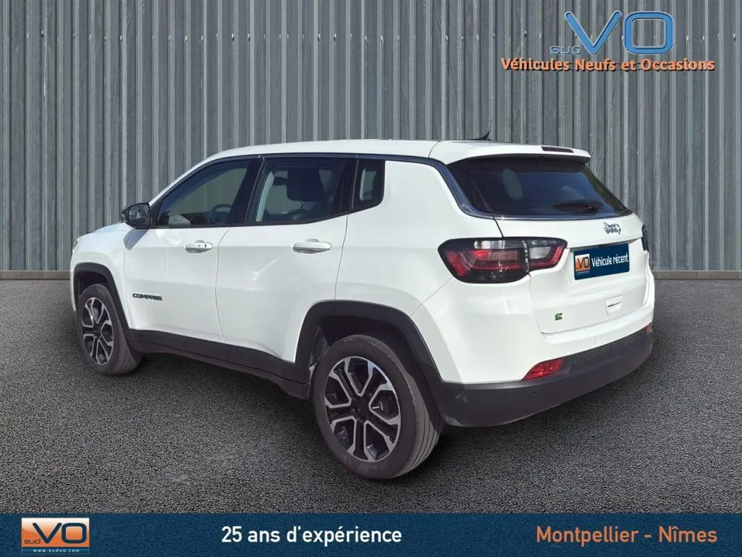 Vue 3/4 arrière gauche d'un Jeep Compass blanc 2024 avec jantes alliage 18 pouces et détails noirs contrastants.