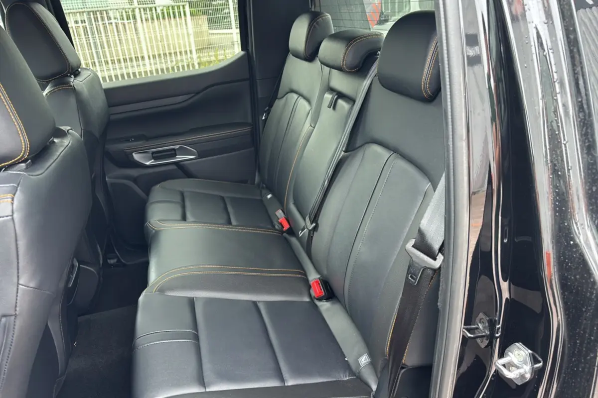 Vue côté gauche de la banquette arrière cuir noir avec surpiqûres orange du Ford Ranger Wildtrak Plus noir agate 2025.