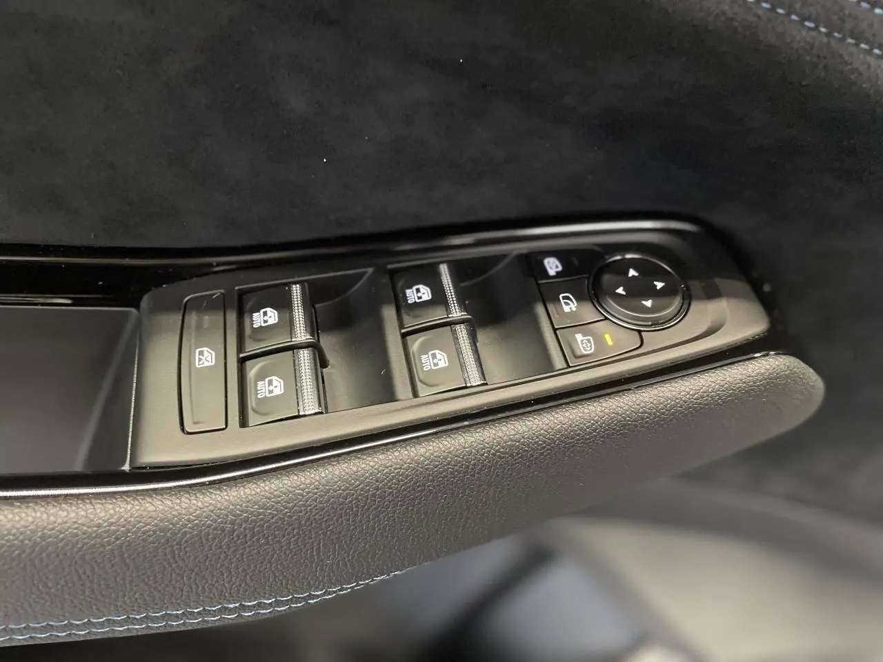 Commande des vitres et rétroviseurs côté conducteur du Renault Austral gris métallisé avec surpiqûres bleues sur la porte intérieure