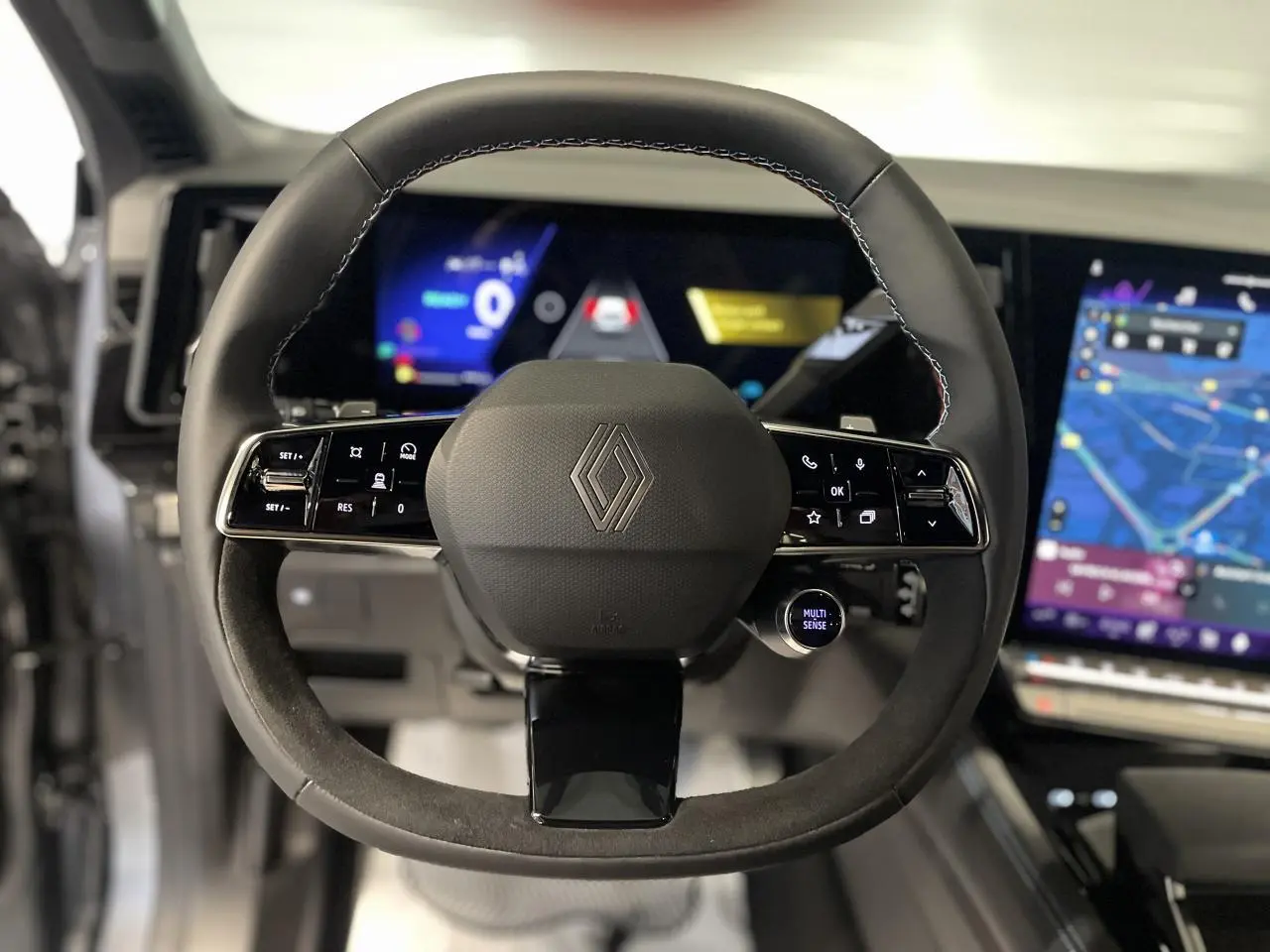 Volant Alcantara avec logo Renault au centre, tableau de bord numérique et écran tactile du Renault Austral 2025 en vue frontale.