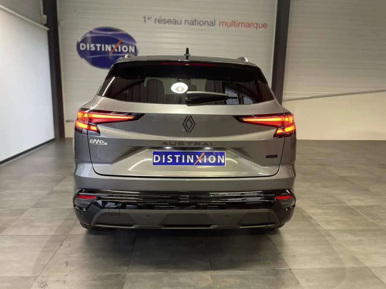 Vue arrière d'un Renault Austral gris métallisé avec feux LED allumés et logo distinctif au centre du hayon.