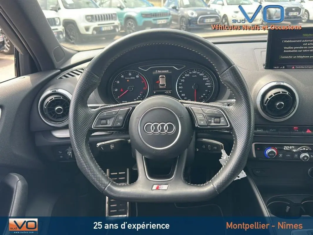 Vue intérieure centrée sur le volant sport multifonctions d'une Audi A3 Sportback gris clair avec tableau de bord digital.